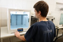 Junger Mann sitzt vor einem 3D-Drucker
