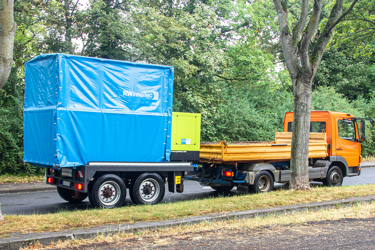 Ein LKW mit Anhänger. Unter der Anhänger-Plane befindet sich die mobile Radiowellen-Anlage von RWInnoTec, mit der das Unternehmen Schlaglöcher zügig, umweltfreundlich und rund um die Uhr sanieren kann. 