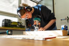 Junge Frau bearbeitet Holz mit einem Werkzeug