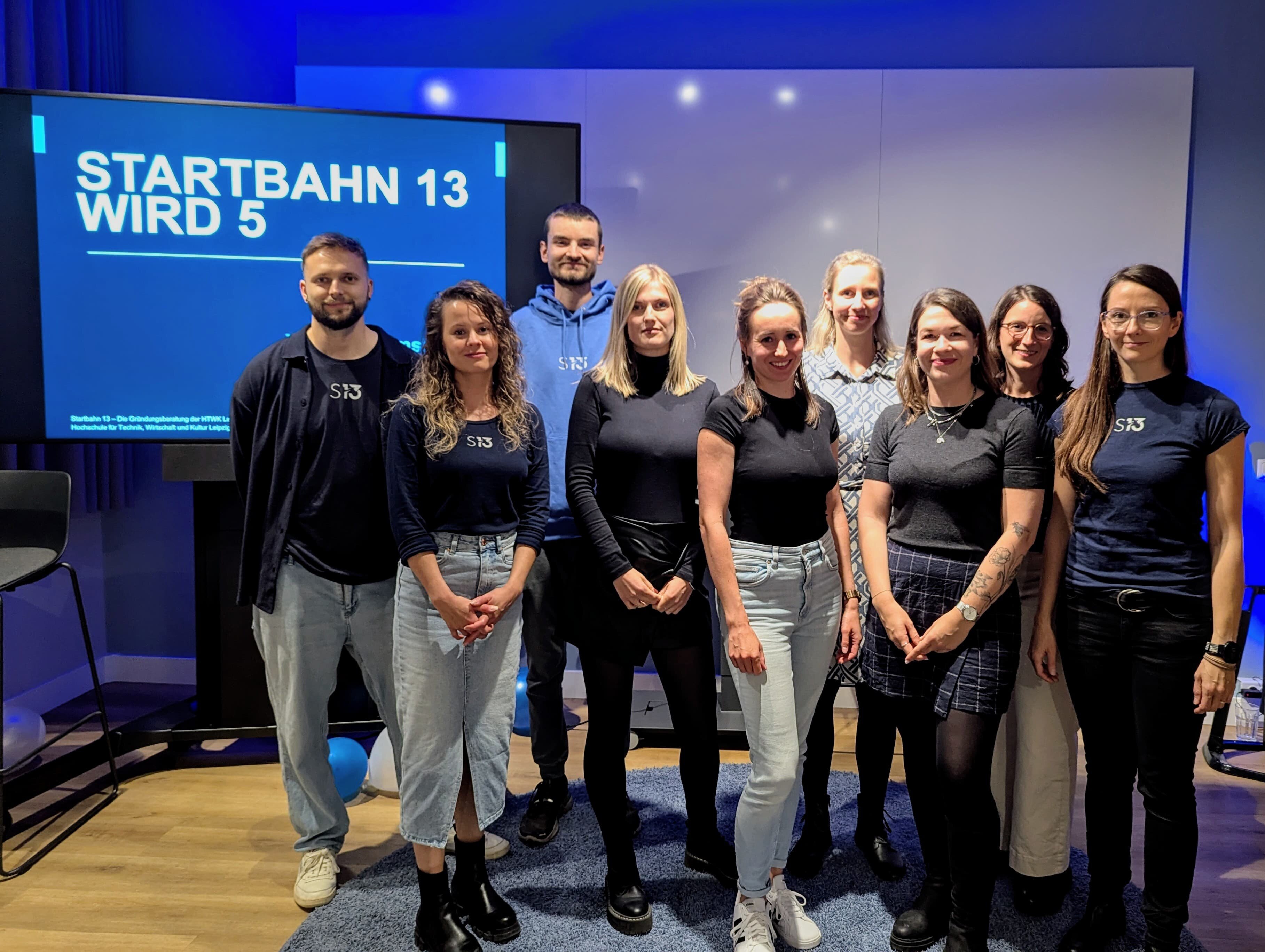 Mehrere Personen des aktuellen und ehemaligen Startbahn 13 Teams blicken freudig in die Kamera